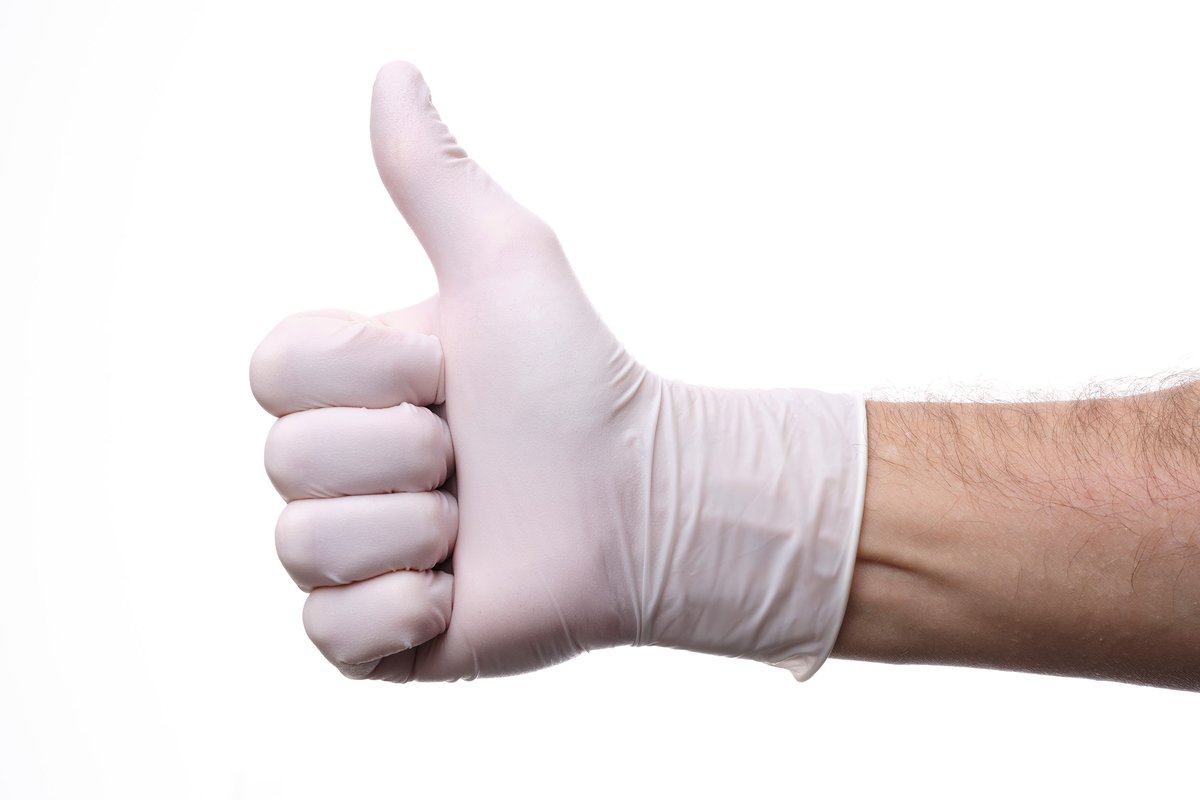 Pearl white natural rubber latex examination glove worn on a hand