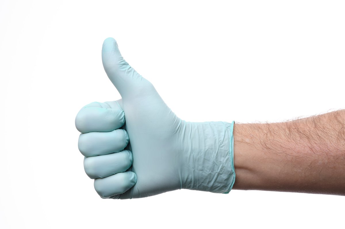 Pastel green biodegradable nitrile examination glove worn on a hand