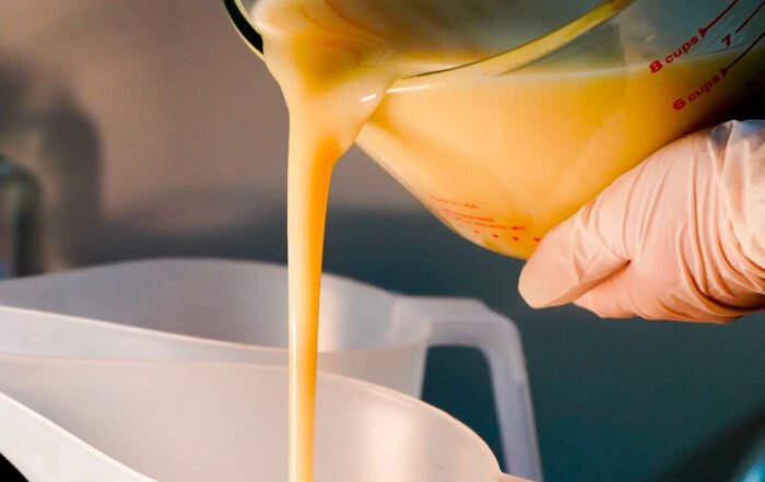 Latex gloves pouring juice into measuring jar
